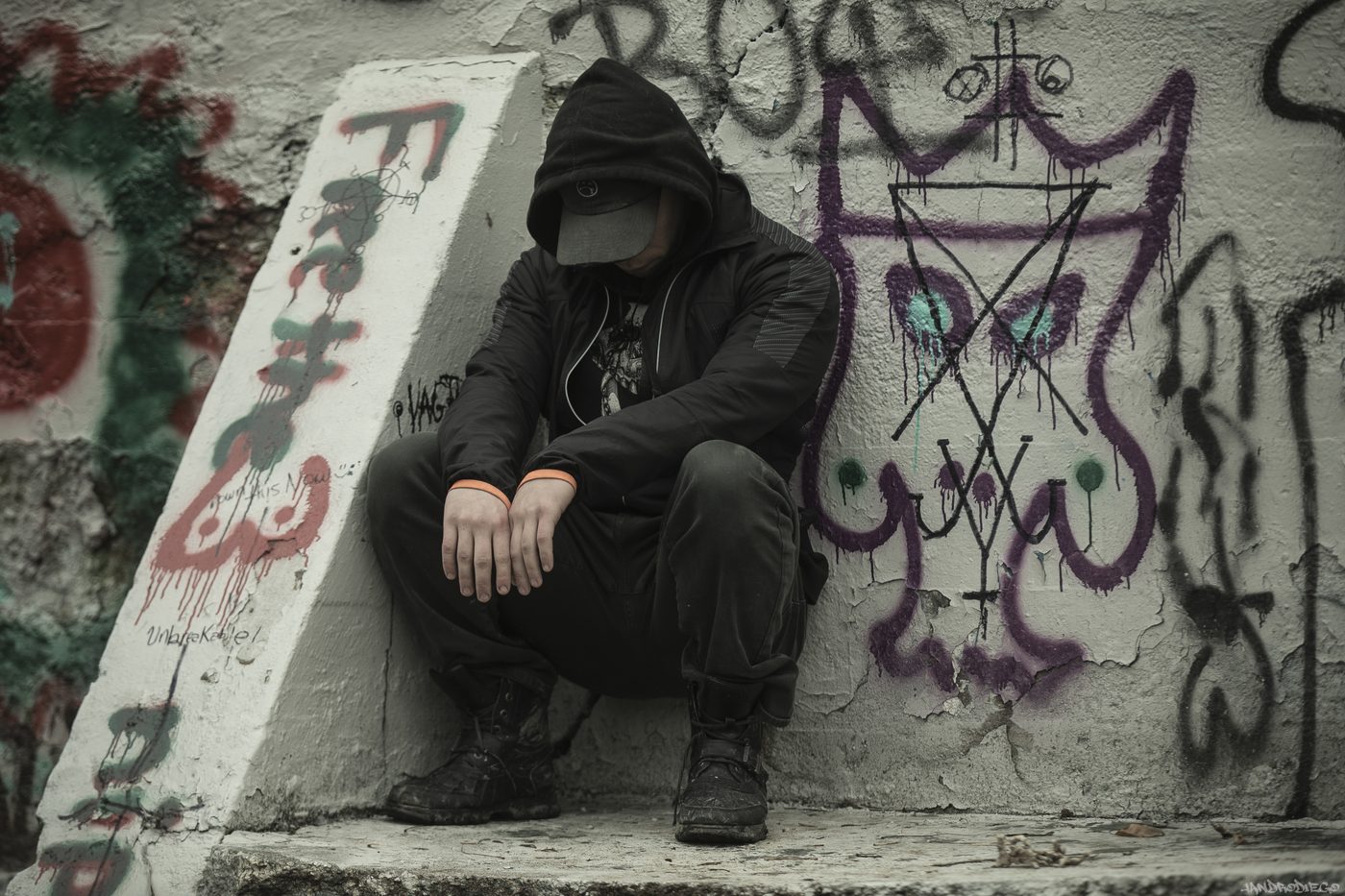 NOSAJ press photo: a figure in black streetwear against a concrete wall